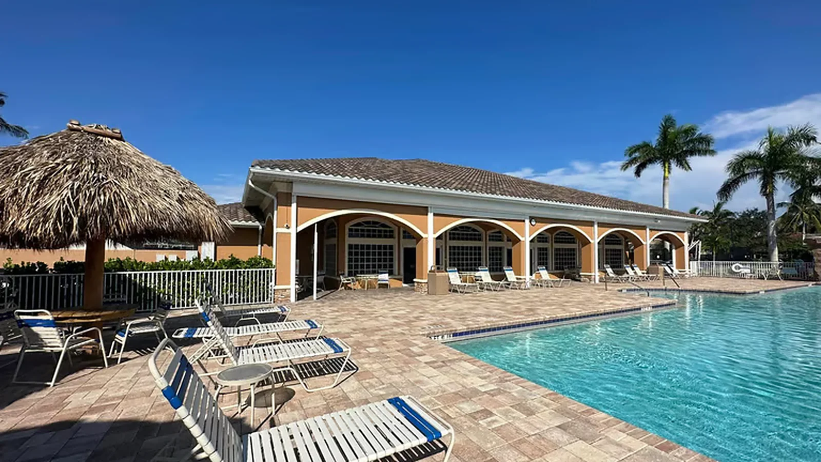 Clubhouse with a tile roof and a long white gutter run beside a community pool