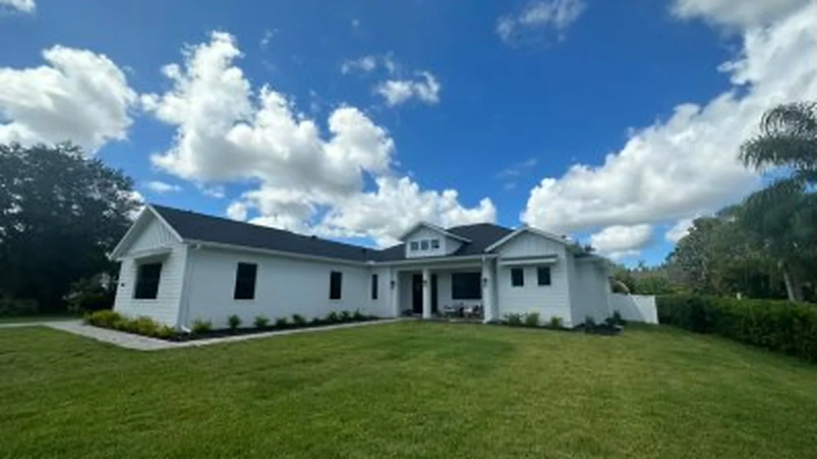 White single-story Suncoast home with a dark roof and a wide green lawn