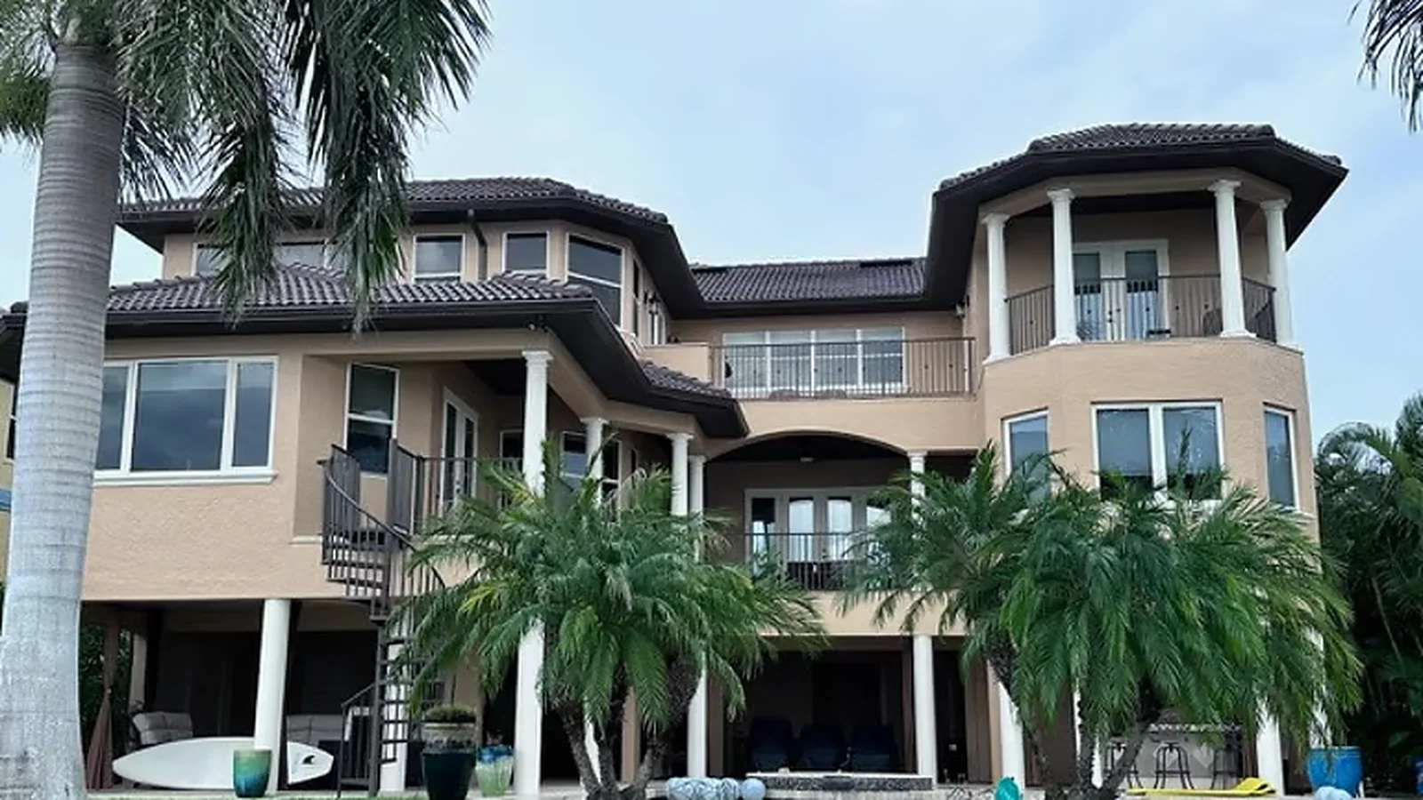Waterfront stucco home with a tile roof, angled bays, and many roofline corners